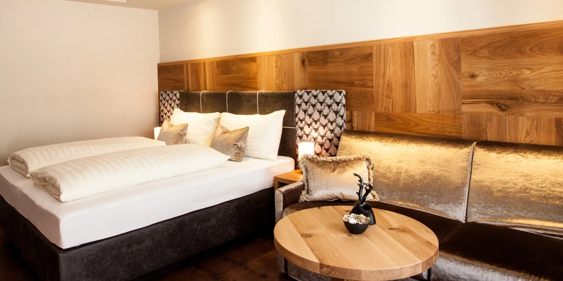 Doppelzimmer Gramaser mit Doppelbett, Holzwand und beleuchteter Sitzlandschaft