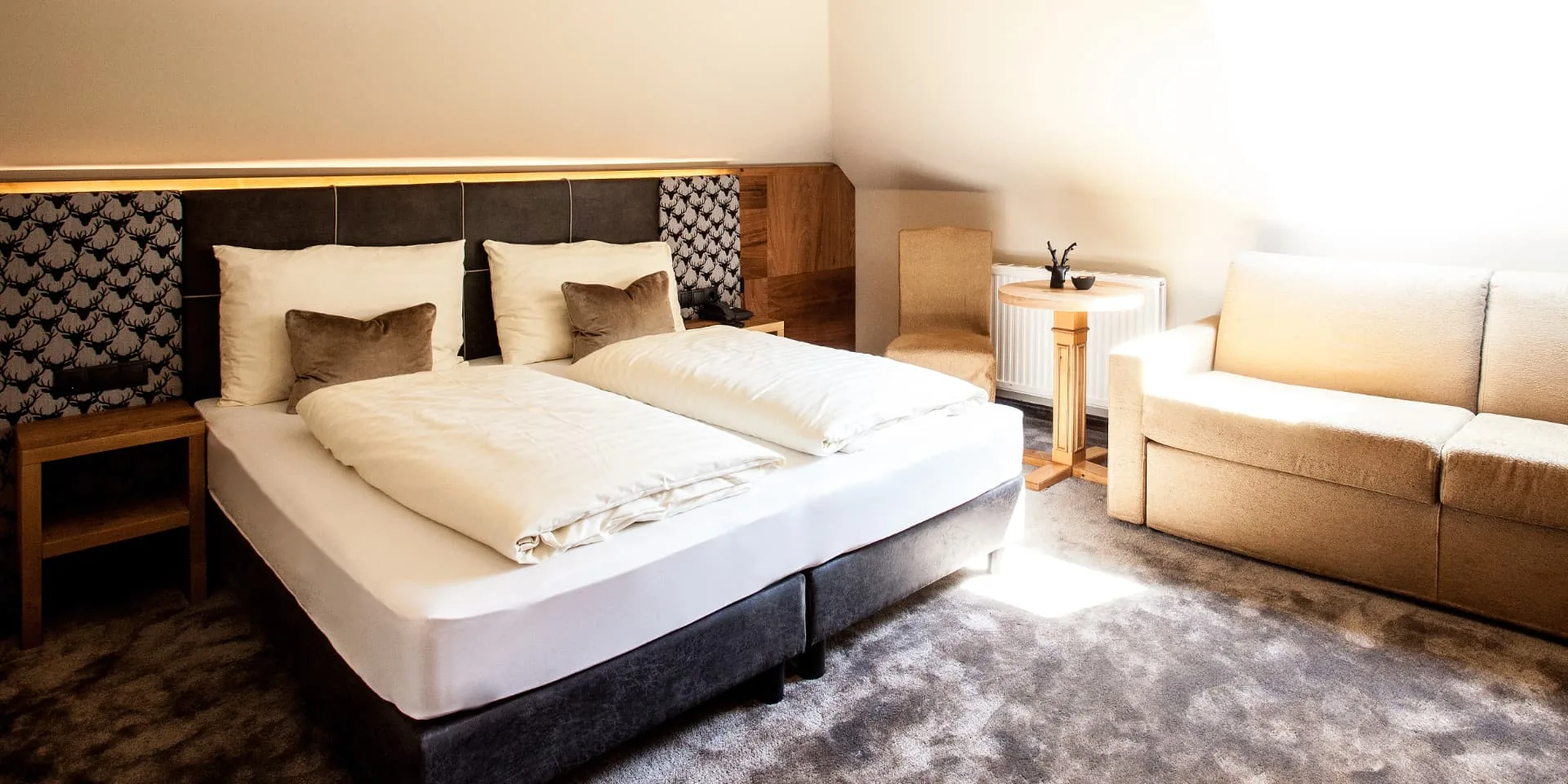 Doppelzimmer Gramaser mit Doppelbett und heller Couch am Fenster